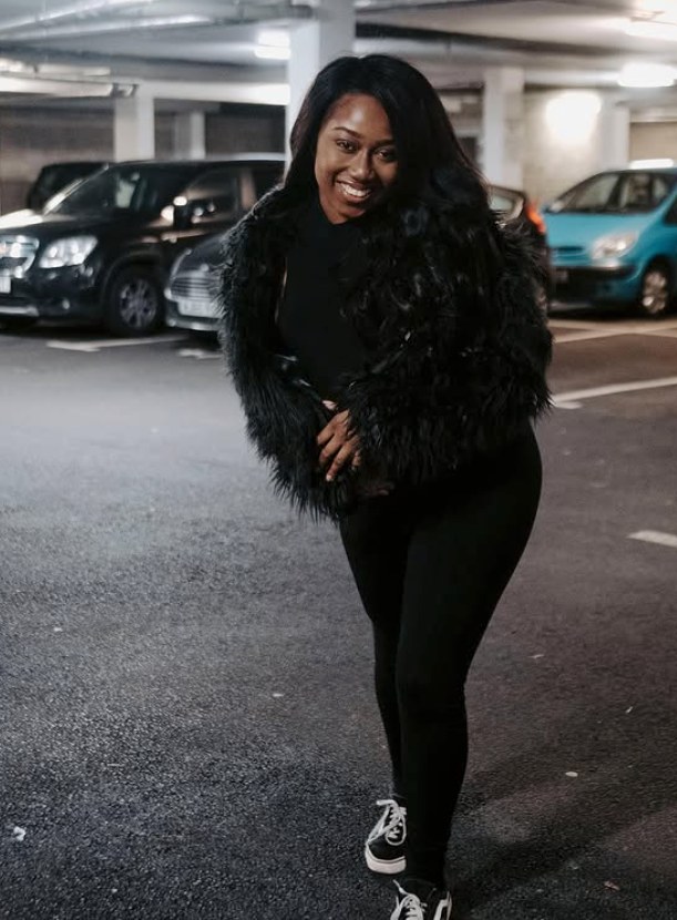 Marcelle Adrianna in a black outfit and textured jacket on a London street.